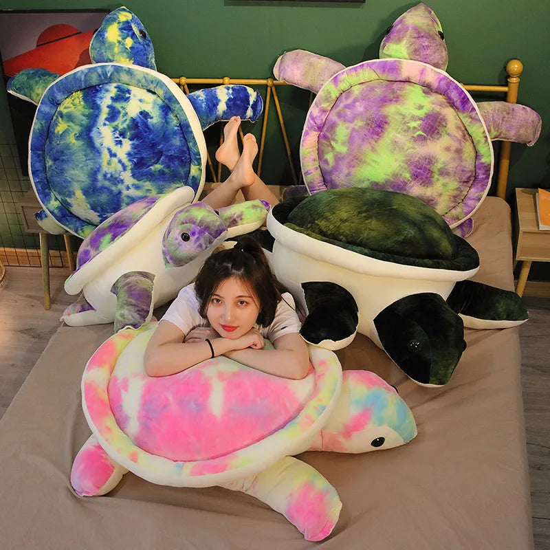Woman sat amongst colourful soft plush turtle toys on a bed.
