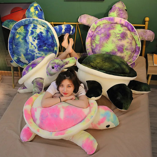 Woman sat amongst colourful soft plush turtle toys on a bed.