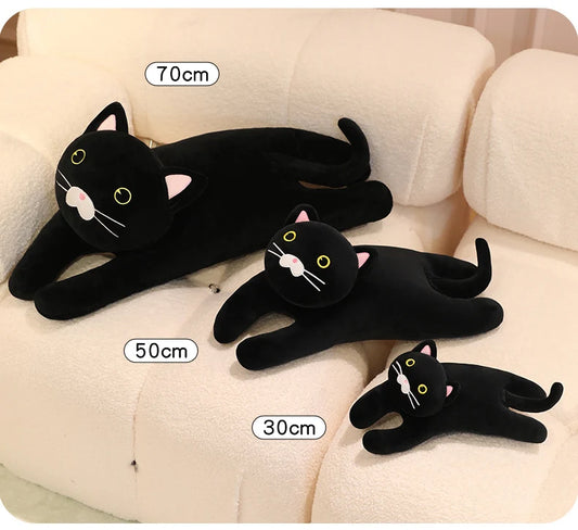 Black cat soft toy with yellow eyes and a long tail, shown in multiple poses on a cream sofa