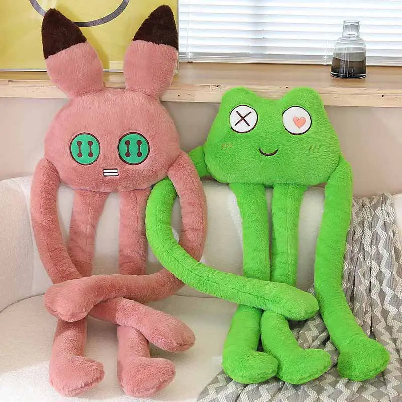 Two plush toys, one pink and one green, sitting on a couch.