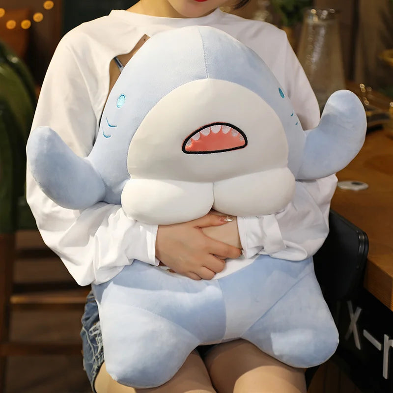 Woman squeezing a soft plush muscular shark toy.