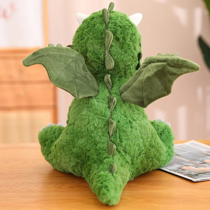 View of the back of a soft plush dragon on a table.