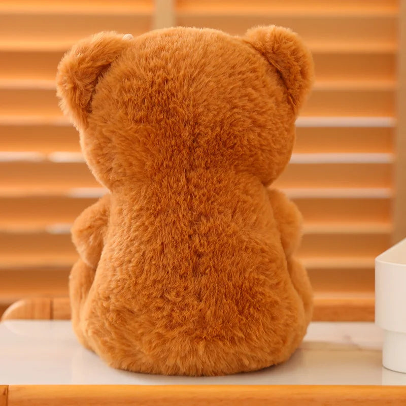 The back of a soft cute brown bear sitting on a wooden surface.