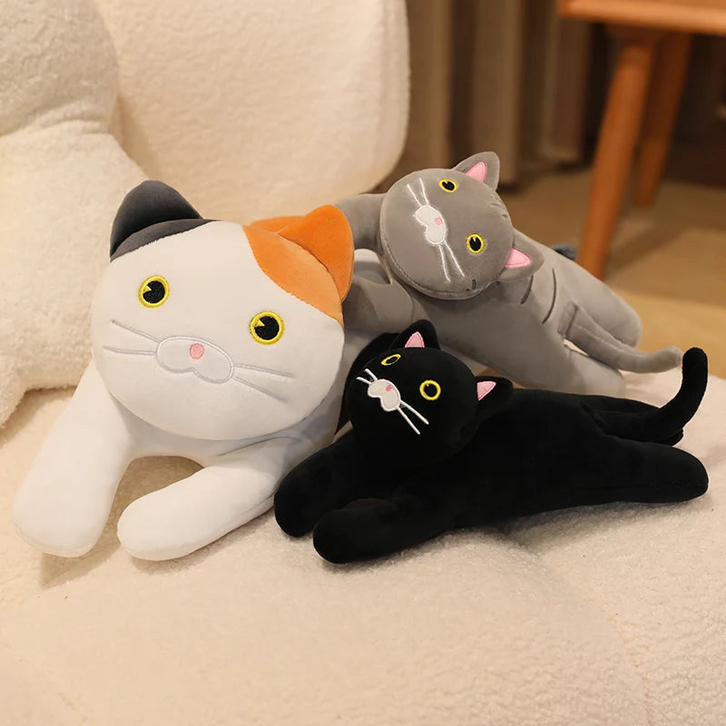 White and grey cat soft toy set with a small black cat plush, styled together on a cream sofa