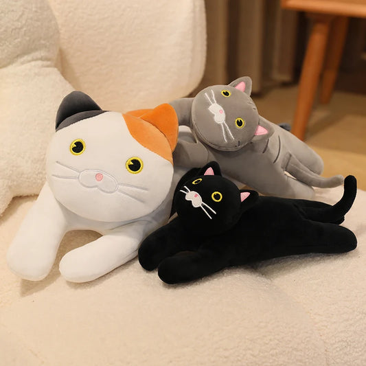 White and grey cat soft toy set with a small black cat plush, styled together on a cream sofa