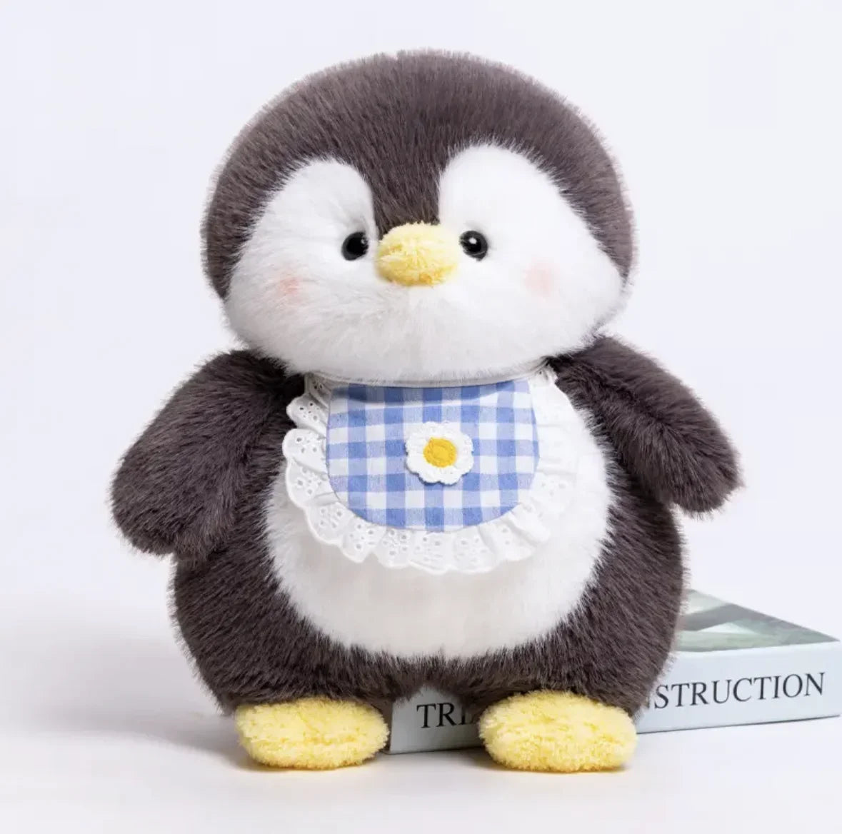 Stuffed penguin toy with a checkered bib on a white background