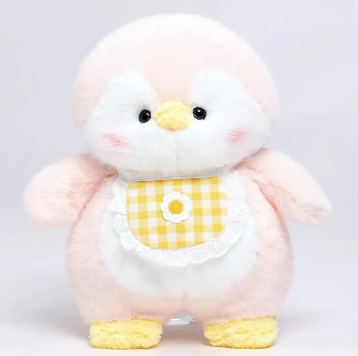 Plush toy penguin with a yellow checkered bib on a light grey background