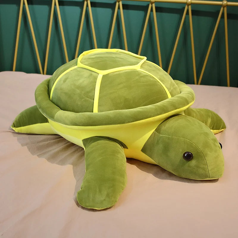 Green soft plush turtle toy with yellow accents on a bed.