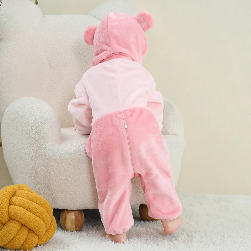 View from behind of a child wearing a pink bear hooded onesie in a cosy room
