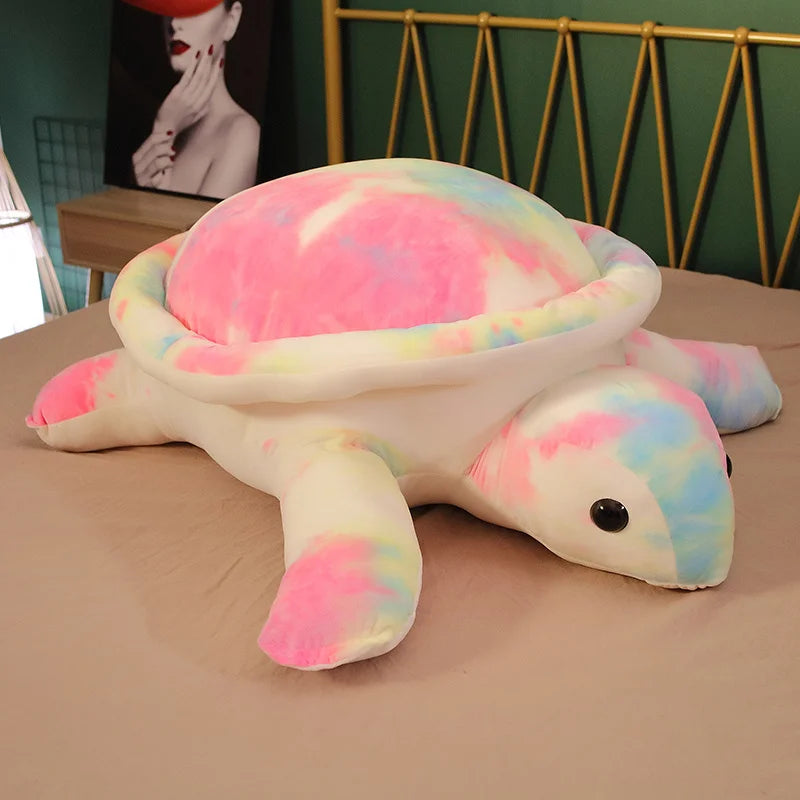 Multicoloured soft plush turtle toy on a bed.