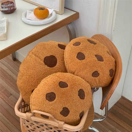 Chocolate chip cookie soft toy set with smiling faces, styled on a chair beside a table in a cosy room