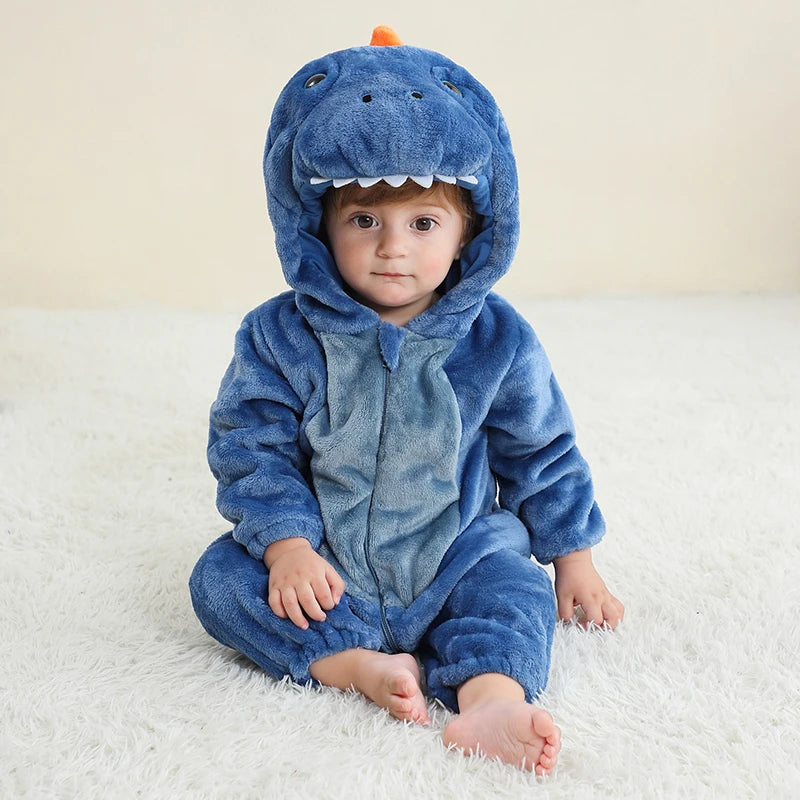 Child wearing a blue dinosaur onesie sitting on a white surface.
