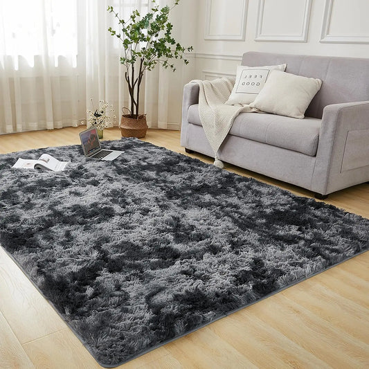 Grey area rug in a living room with a sofa and laptop.