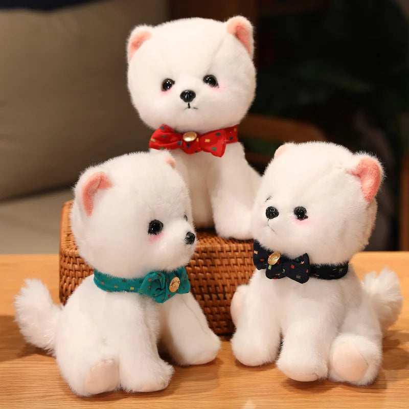 Three white plush toys with colourful bow ties on a wooden surface.