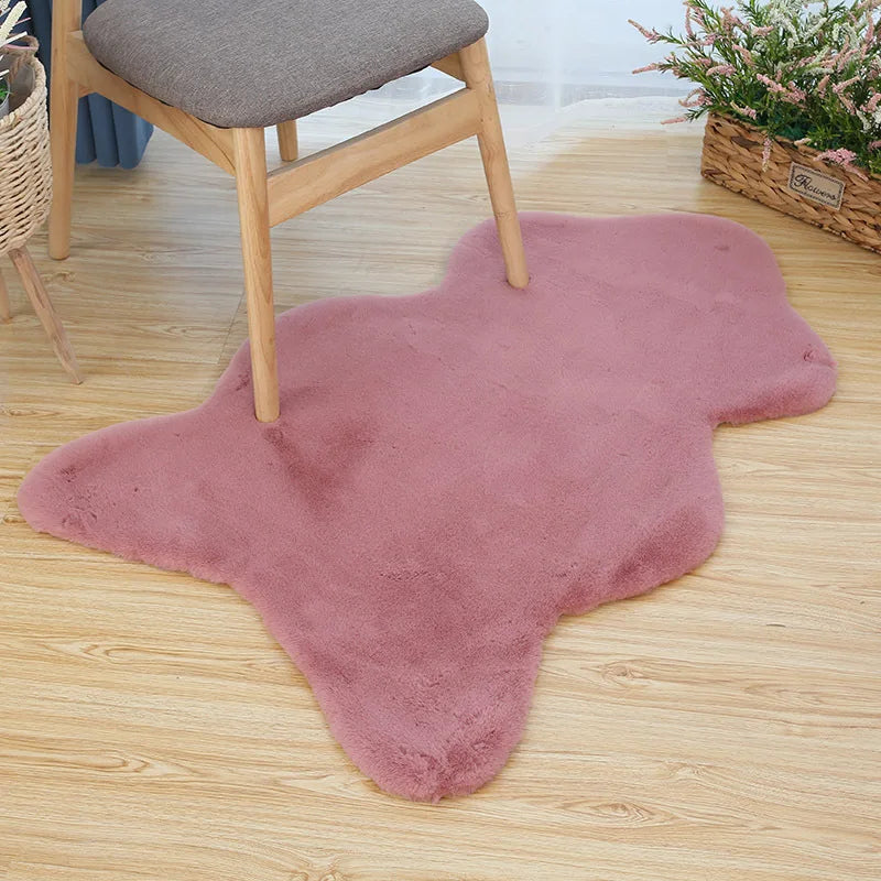 Dusty pink fun-shaped faux rabbit fur rug placed on a wooden floor beneath a chair