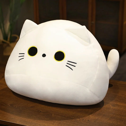 White soft plush cat toy on a wooden surface with a burred background.