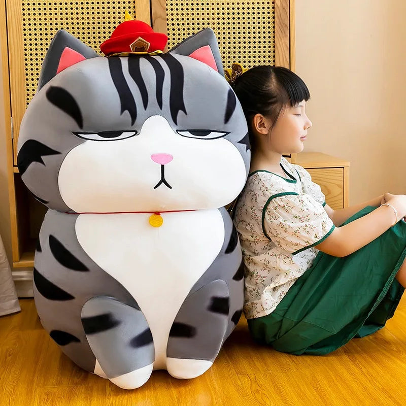Large cat-shaped plush toy next to a child sitting on the floor.