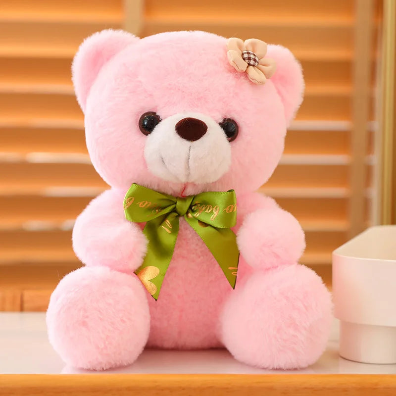 Pink soft plush teddy bear sitting on a wooden surface