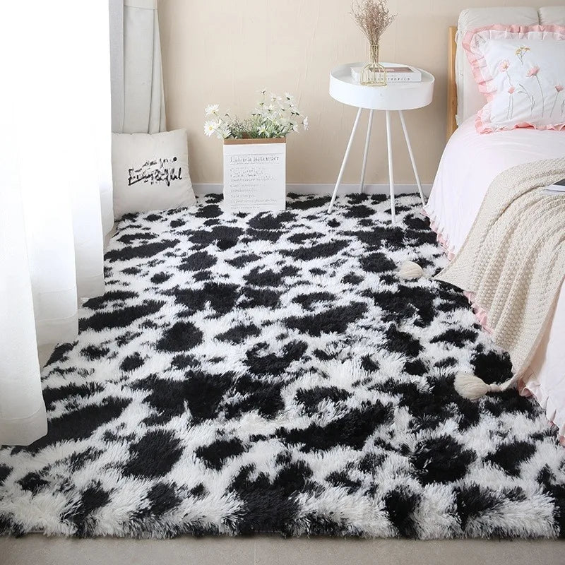 Black and white cow print rectangular plush rug placed on the floor in a bedroom