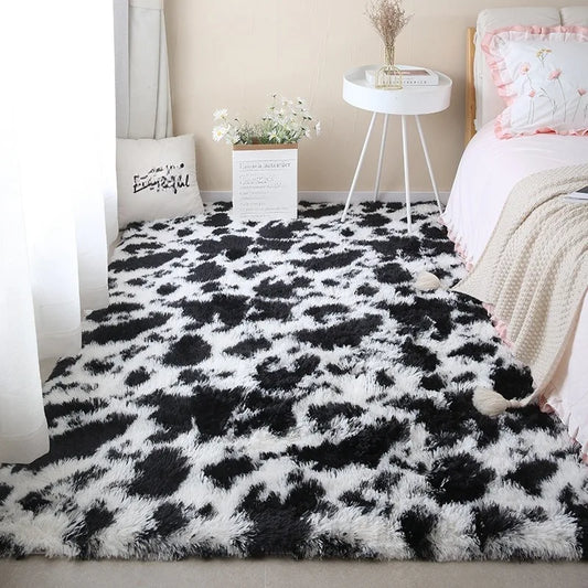 Black and white cow print rectangular plush rug placed on the floor in a bedroom