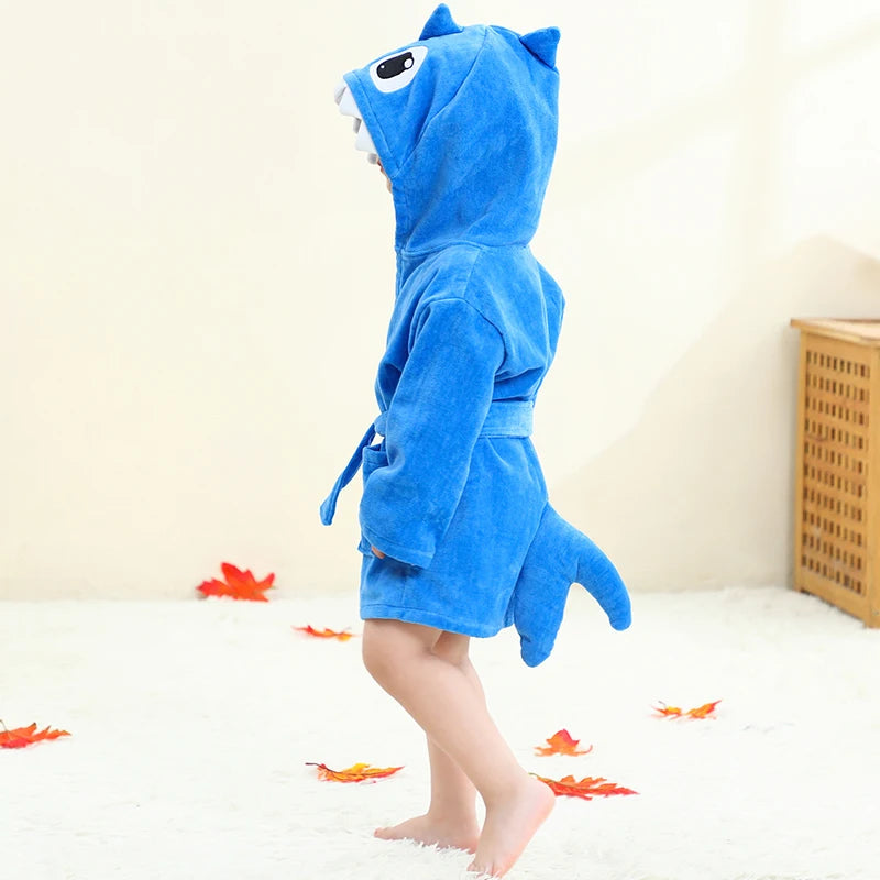 Child wearing a blue shark-shaped robe on a light background