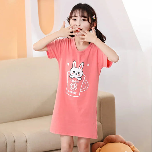 Child wearing a pink nightgown with a cartoon design, in a cosy setting.