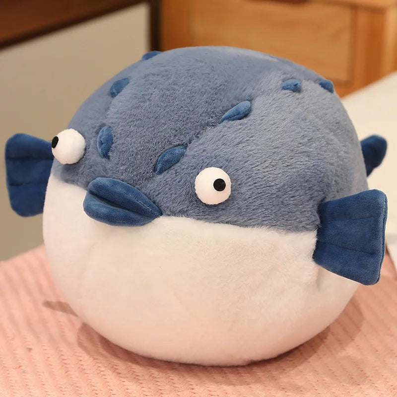 Plush toy resembling a blue and white pufferfish on a wooden surface