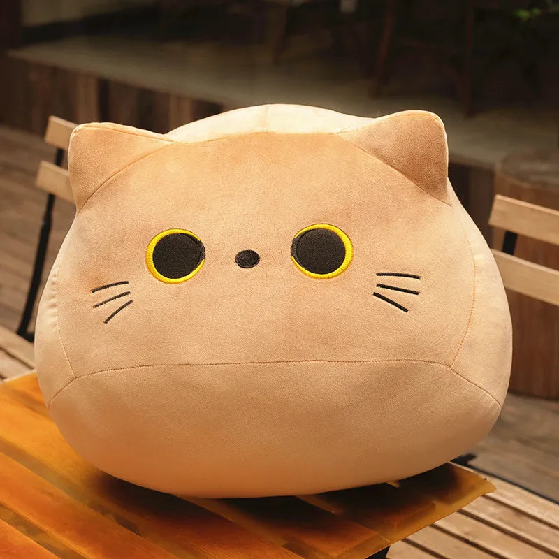 Orange soft plush cat toy on a wooden surface with a burred background.