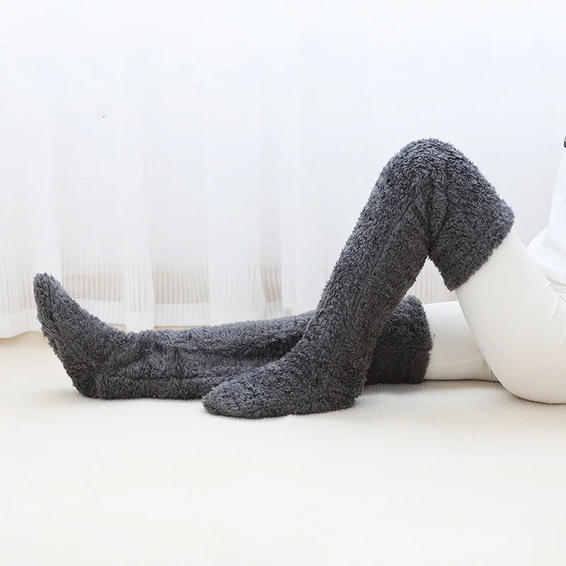 Dark grey fuzzy socks on a white surface with a blurred background