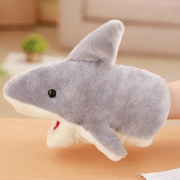Plush shark hand puppet on a wooden surface with a blurred background