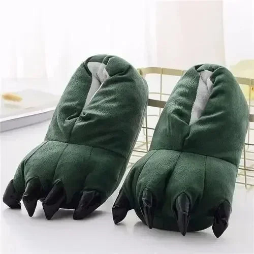 Green paw-shaped slippers with black nails on a white surface.