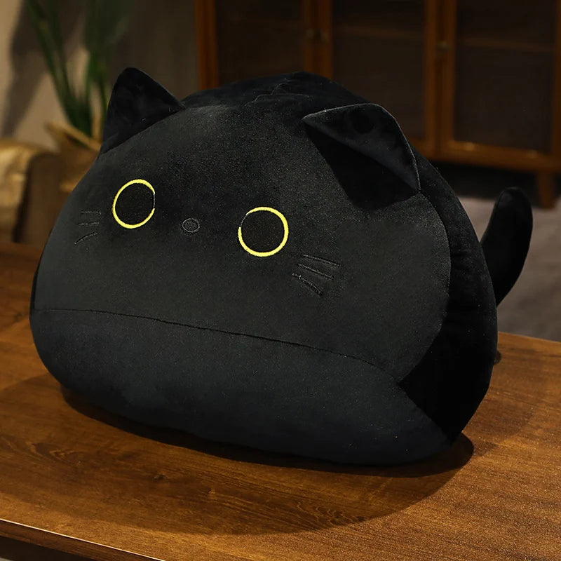 Black soft plush cat toy on a wooden surface with a burred background.