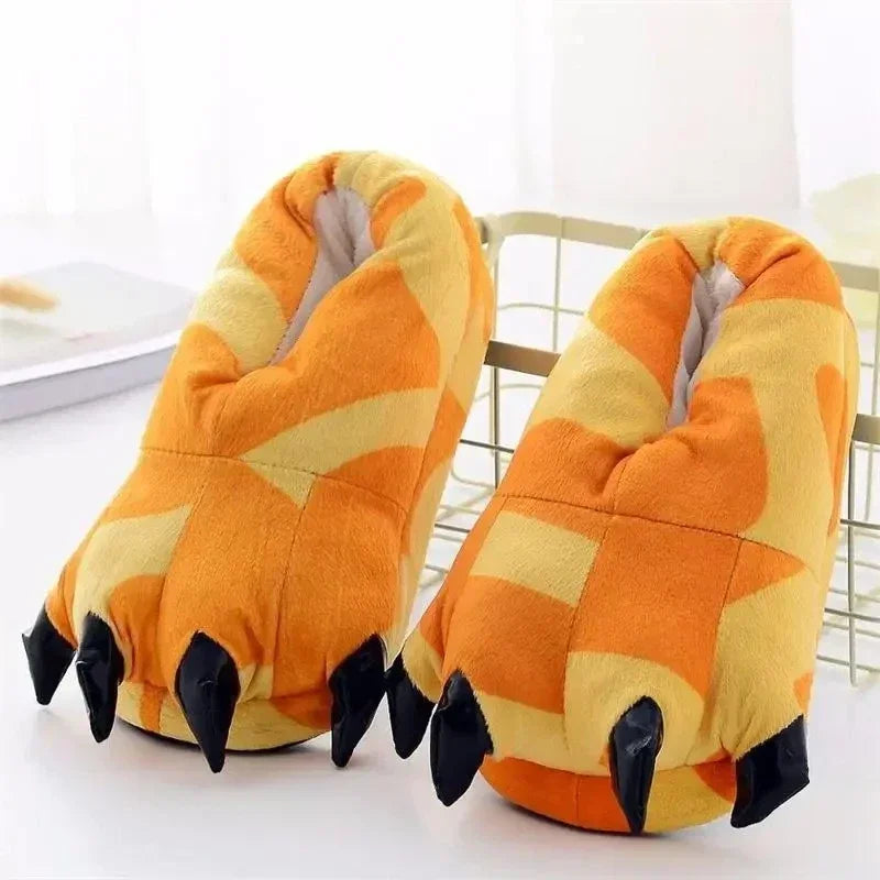 Pair of orange and yellow paw-shaped slippers with black claws on a white surface.