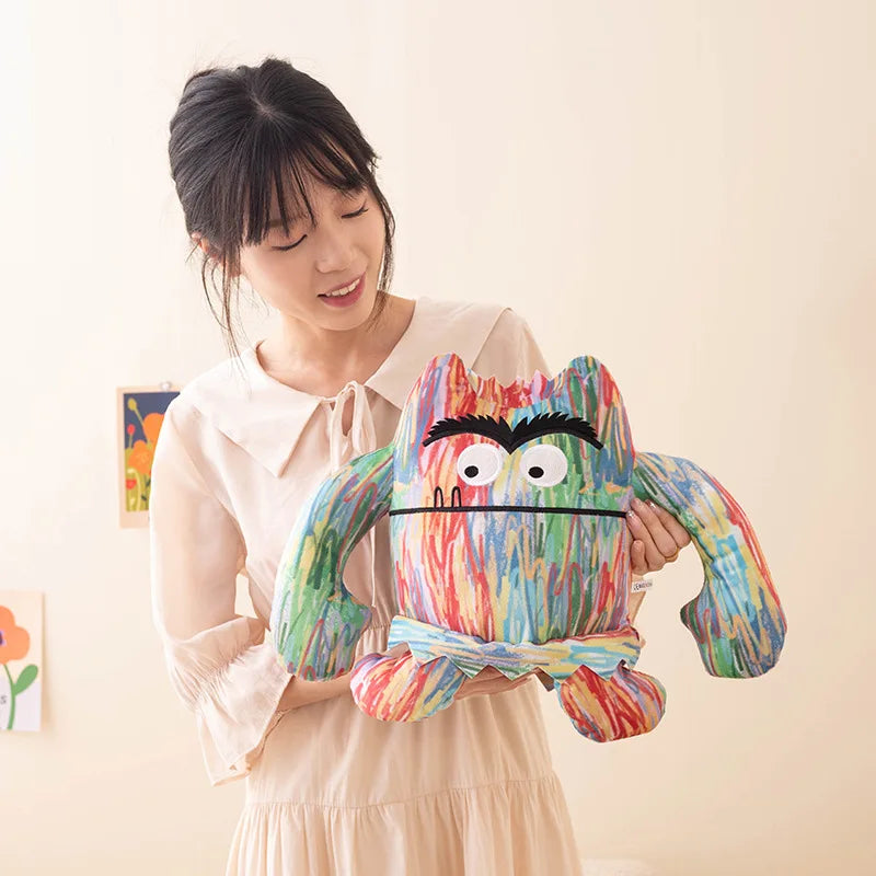 Person holding a colorful plush toy with cartoonish face against a plain background