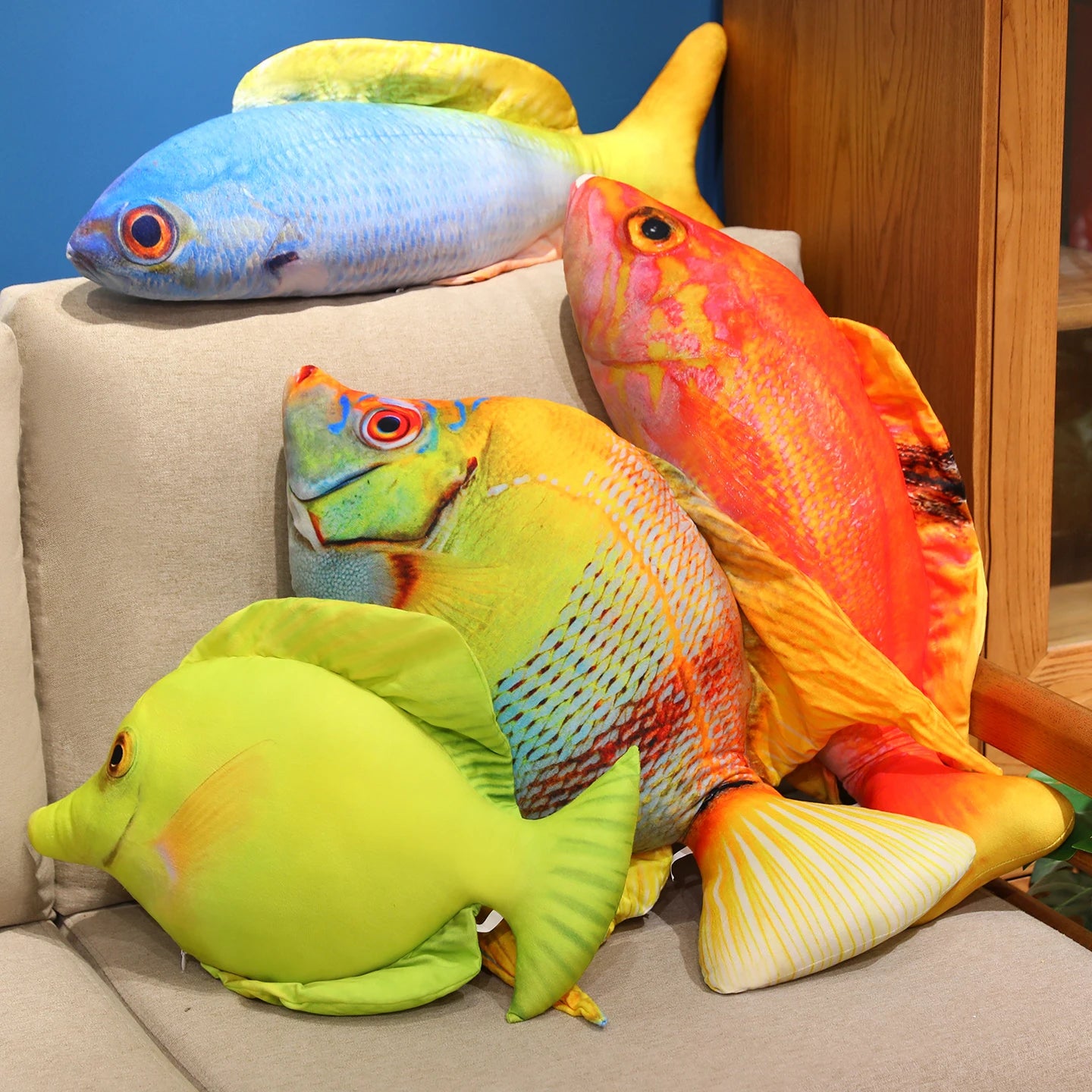 Colourful fish soft toy set in blue, green and orange, stacked together on a couch
