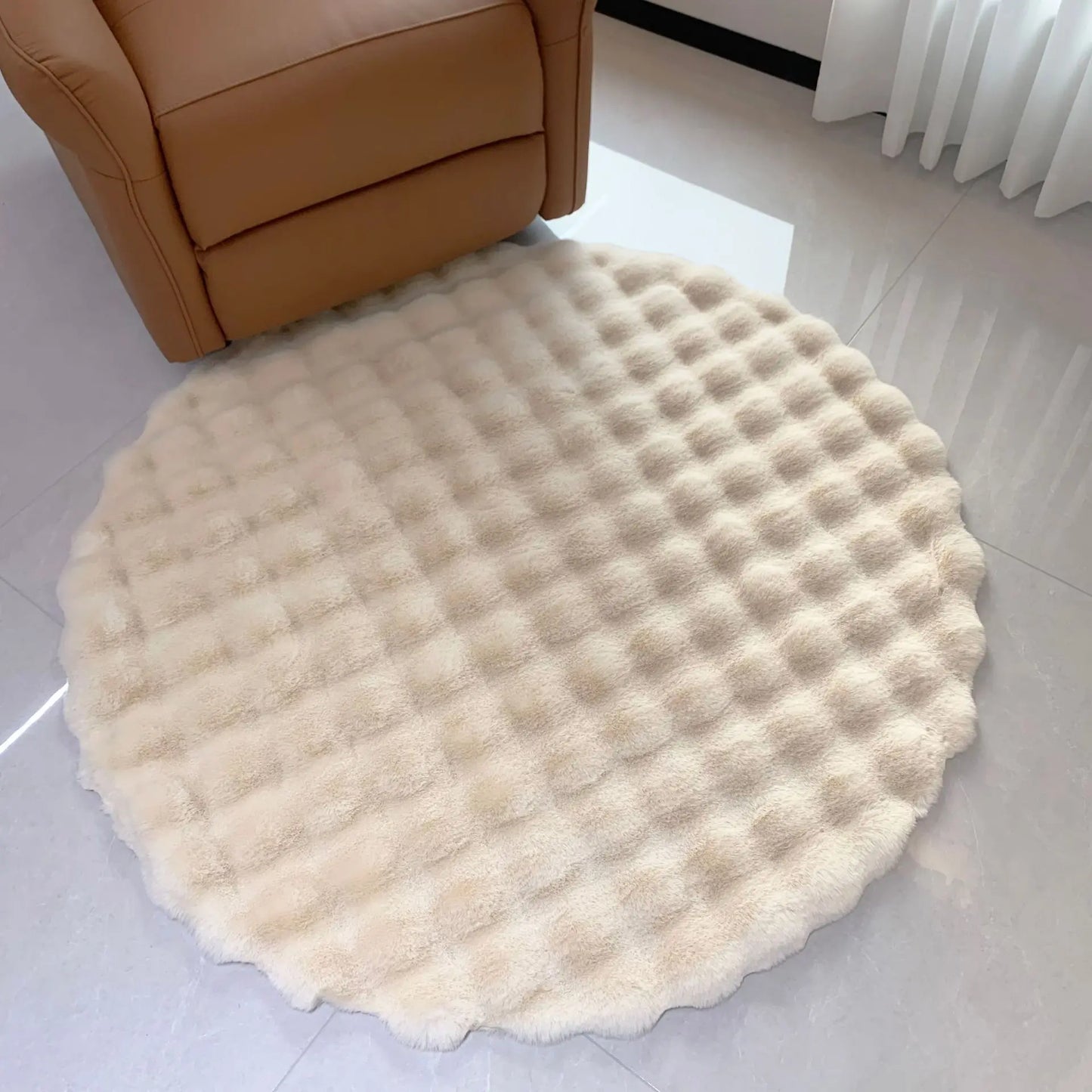 Cream round bubble velvet plush rug placed on a light floor beside a tan chair