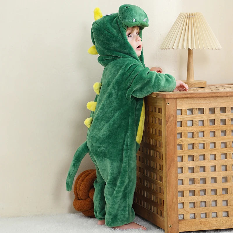 Child in a green dinosaur costume standing next to a wooden basket.