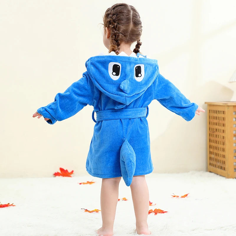 Child wearing a blue shark-themed robe on a light background