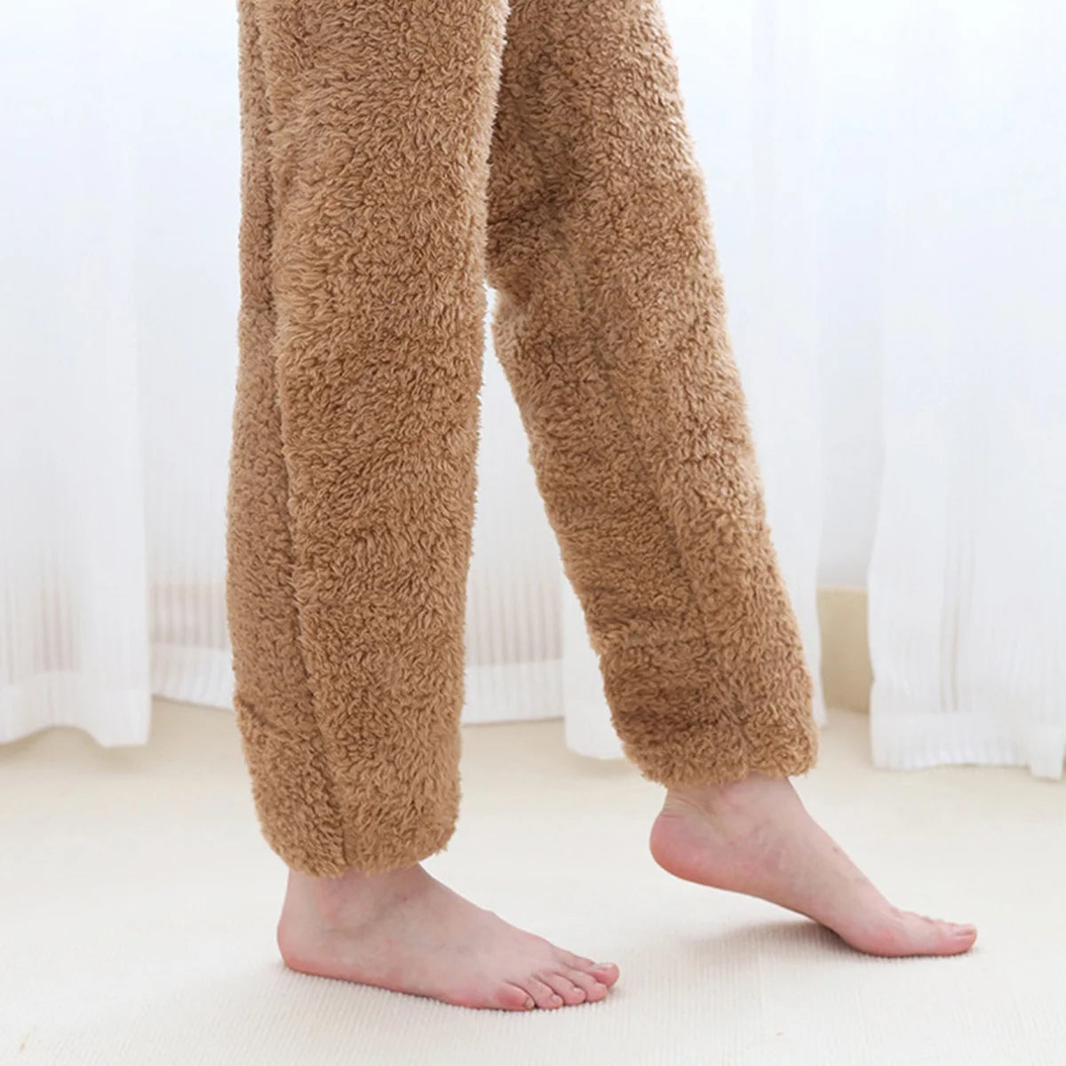 Brown fuzzy leg warmers worn by a person on a light-coloured floor with white curtains in the background