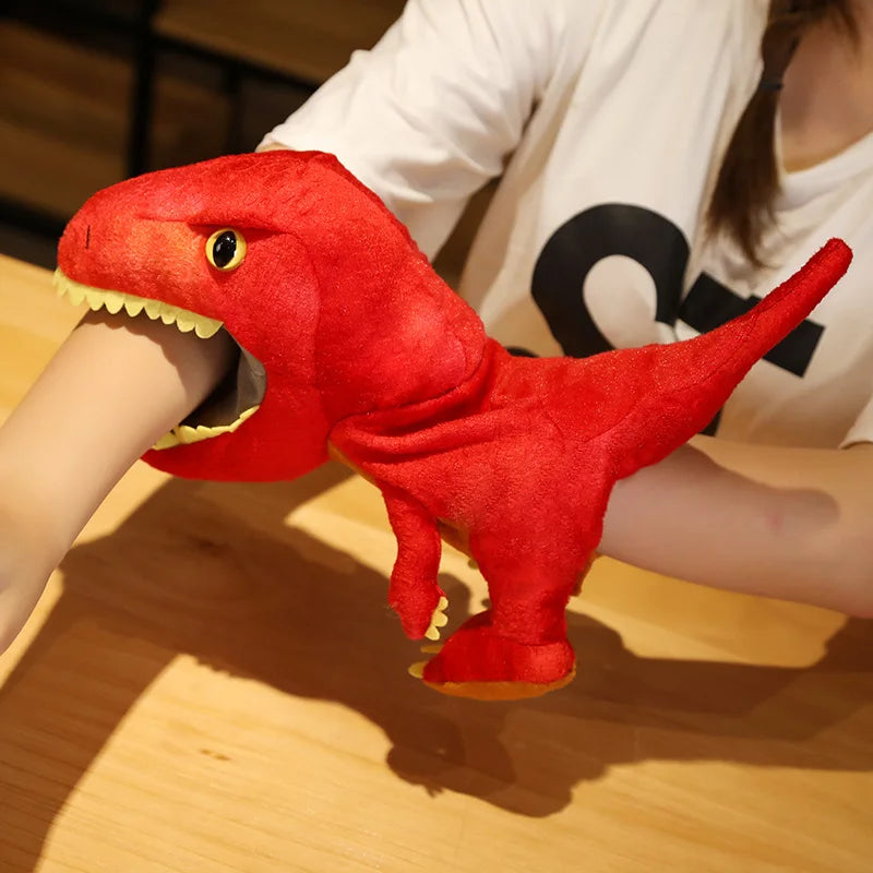 Red dinosaur plush hand puppet held by a person on a wooden surface