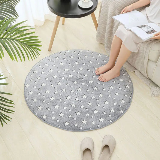Round grey kids rug with white star print placed on a light wood floor beside a sofa
