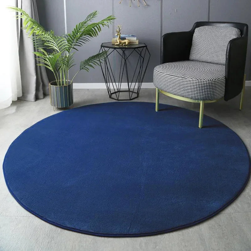 Round blue rug in a room with a black and white chair, plant, and side table.