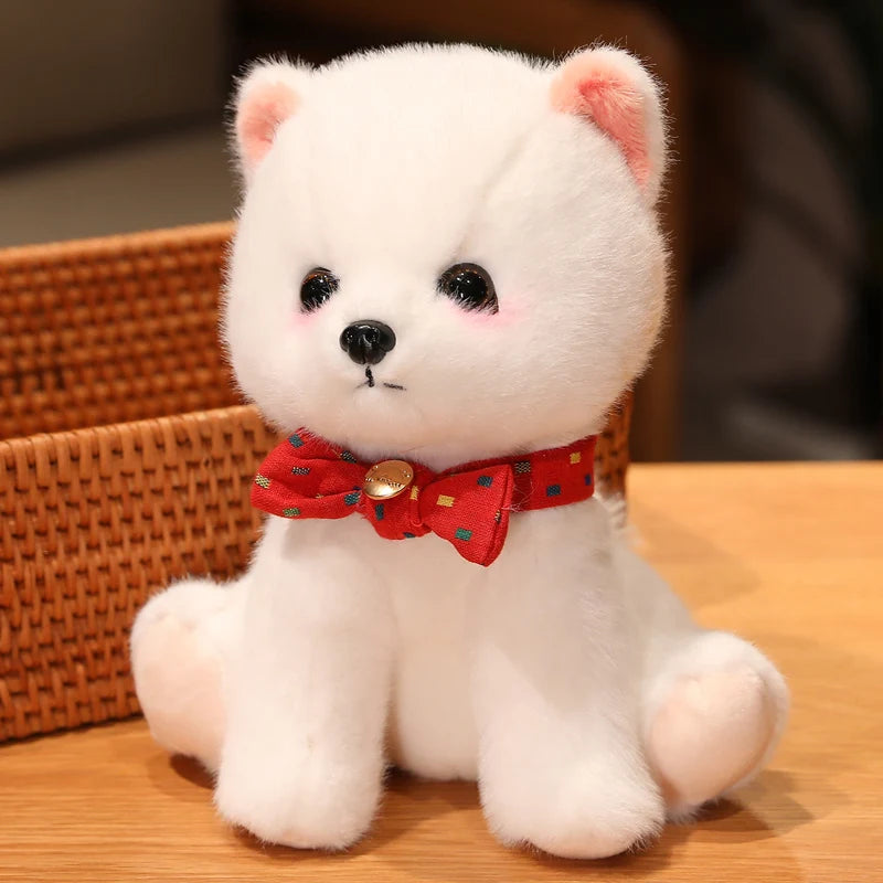 White teddy bear with a red bow tie sitting on a wooden surface.