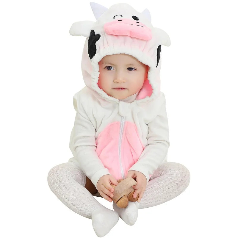 Baby wearing a cow hooded onesie on a white surface. 