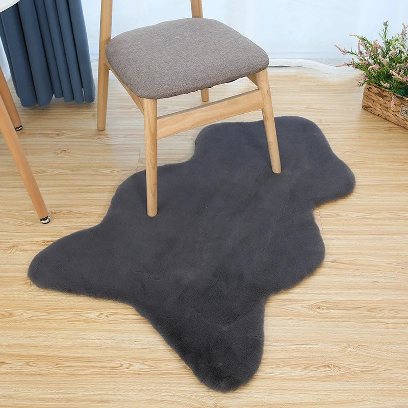 Dark grey fun-shaped faux rabbit fur rug placed on a wooden floor beneath a chair