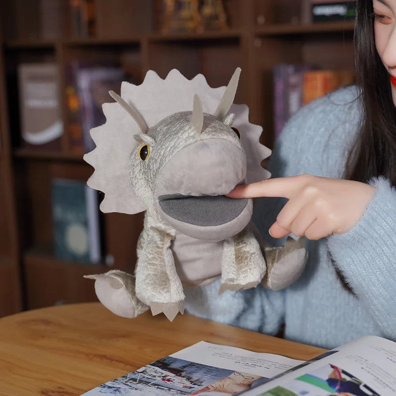 Person holding a triceratops plush hand puppet with a blurred bookshelf in the background