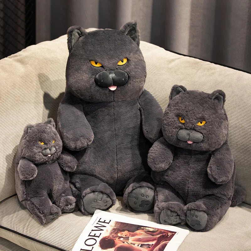 Three grey plush toys resembling cats on a beige couch.