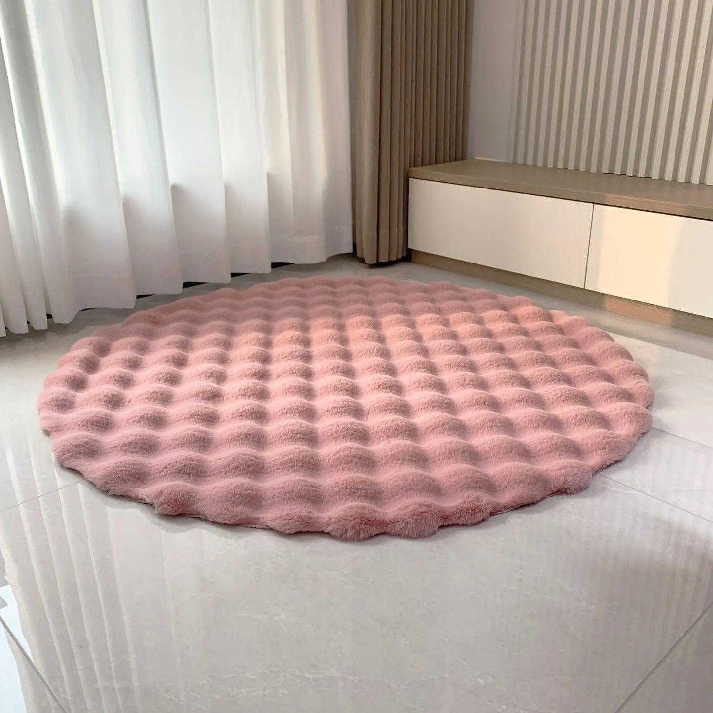 Dusty pink round bubble velvet plush rug shown on a light tiled floor in a softly styled room