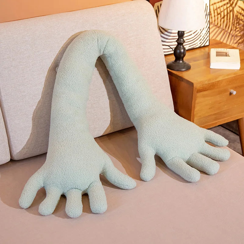 Large plush arm pillow on a sofa with a lamp and wooden side table in the background.