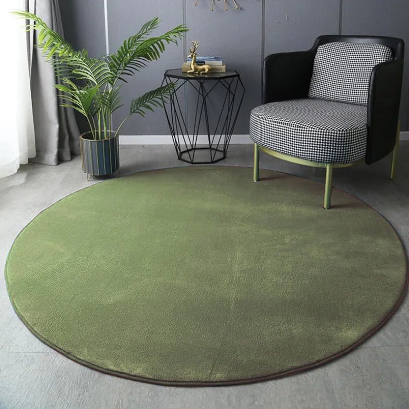 Round green rug in a room with a black and white checkered chair, small table, and plant.